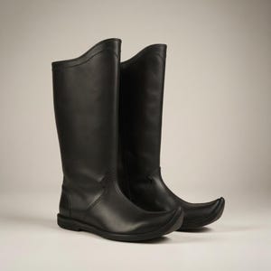 Könnte beinhalten: Ein Paar schwarze Lederstiefel mit spitzer Zehenpartie und hohem Schaft. Die Stiefel haben einen geschwungenen oberen Rand und eine flache Sohle. Die Stiefel sind aus glattem, glänzendem Leder.