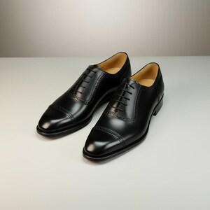 May include: A pair of black leather dress shoes with a classic Oxford design. The shoes feature a cap toe, intricate stitching details, and a lace-up closure. The polished finish gives them a formal and elegant appearance, suitable for business or special occasions.