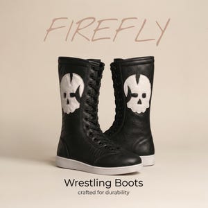 K&ouml;nnte beinhalten: Ein Paar schwarze Schn&uuml;r-Wrestlingstiefel mit einer wei&szlig;en Totenkopf-Applikation an der Seite jedes Stiefels. Der Text FIREFLY steht &uuml;ber den Stiefeln und der Text Wrestling Boots crafted for durability steht unter den Stiefeln.