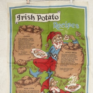 May include: A vintage linen tea towel with a green background and illustrations of gnomes. The towel features three Irish potato recipes: Champ, Irish Stew, and Potato Bread. The text on the towel reads "Irish Potato Recipes".