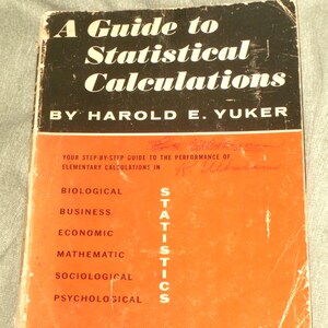 May include: A softcover book titled A Guide to Statistical Calculations by Harold E. Yuker. The cover is black on the top half with white text and orange on the bottom half with black text listing fields including biological and business.
