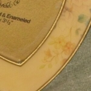 Puede incluir: Un marco de fotos dorado en forma de coraz&oacute;n con un dise&ntilde;o floral. El marco mide 3 1/2 pulgadas y tiene un borde dorado.