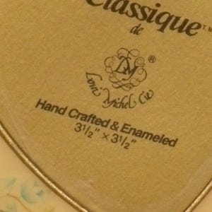 Puede incluir: Una caja dorada en forma de coraz&oacute;n con un dise&ntilde;o floral y el texto "Classique de Lori Michel Cie Hand Crafted & Enameled 3 1/2" x 3 1/2""
