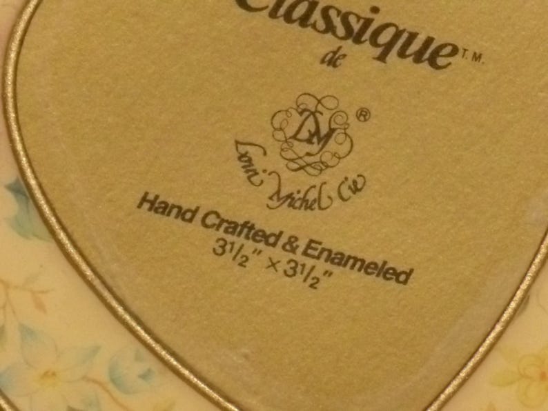 Puede incluir: Una caja dorada en forma de coraz&oacute;n con un dise&ntilde;o floral y el texto "Classique de Lori Michel Cie Hand Crafted & Enameled 3 1/2" x 3 1/2""