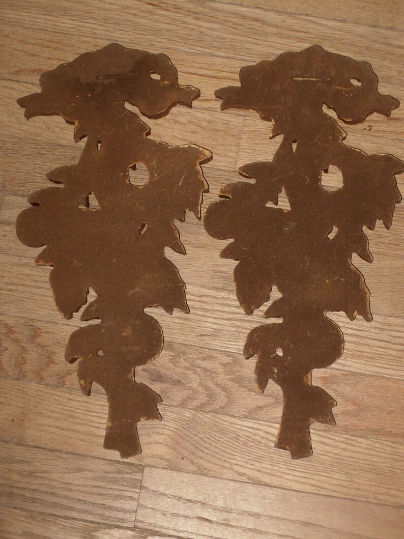 May include: A pair of brown wooden wall decor pieces shaped like stylized floral designs.