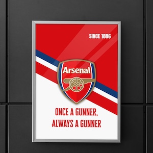 May include: A rectangular framed poster featuring the Arsenal football club crest centered on a red and white diagonal background with blue accents. The text reads "SINCE 1886" at the top right and "ONCE A GUNNER, ALWAYS A GUNNER" at the bottom.