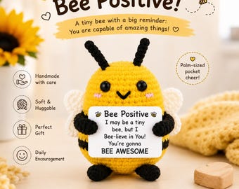 Pode incluir: Uma peluche de abelha em croché amarela e preta que segura um sinal retangular branco com o texto: Bee Positive, I may be a tiny bee, but I Bee-lieve in You! You're gonna BEE AWESOME. A abelha tem antenas pretas, pequenas asas brancas e olhos pretos.