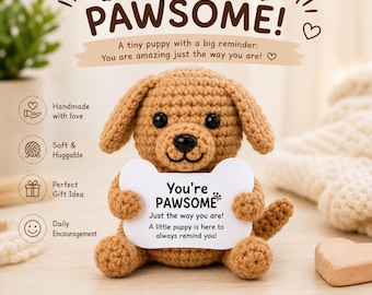 Pode incluir: Um cachorrinho marrom de crochê segurando uma placa em forma de osso que diz "You're PAWSOME!". A imagem inclui texto que diz "Feito à mão com amor", "Macio e abraçável", "Ideia de presente perfeita" e "Encorajamento diário".