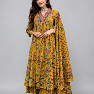 May include: Mustard yellow floral print ensemble featuring a long-sleeved tunic with a V-neckline and matching palazzo pants. The outfit includes a coordinating scarf. The floral pattern incorporates red, blue, and green accents.