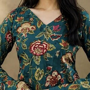 May include: Teal-colored top with a V-neck and long sleeves, adorned with a floral pattern in shades of red, cream, and green. The fabric appears to be a soft, flowing material, suitable for casual wear.