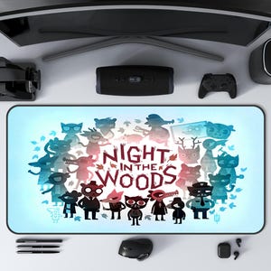 May include: A rectangular mouse mat with a light blue gradient background, featuring cartoon characters and the text "NIGHT IN THE WOODS". The design includes various animal-like figures. A computer mouse, pens, and other tech accessories surround the mouse mat.