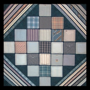 May include: A quilt made from squares of different patterned fabric, primarily blue and white, with a dark blue background. The squares are arranged in a diamond pattern.