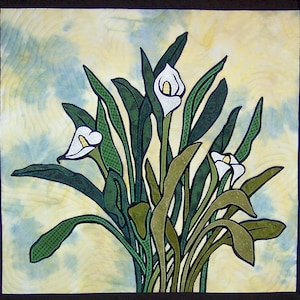 May include: A quilted wall art piece featuring a cluster of white calla lilies with green leaves against a yellow and blue background.