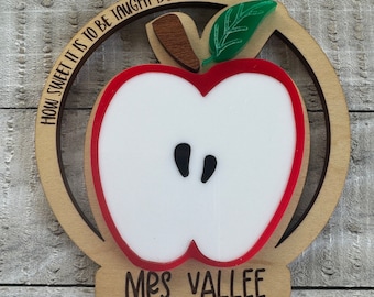 May include: Wooden apple ornament with a red apple cutout and the text "How sweet it is to be taught by you!" and "Mrs. Vallee" on the bottom.