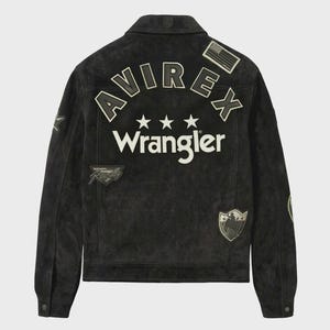 Puede incluir: Una chaqueta de ante negro con el texto AVIREX y Wrangler en letras blancas en la espalda. El dise&ntilde;o incluye tres estrellas blancas, un peque&ntilde;o parche de la bandera estadounidense, un parche de Wrangler Racing y un parche en forma de escudo con un vaquero.