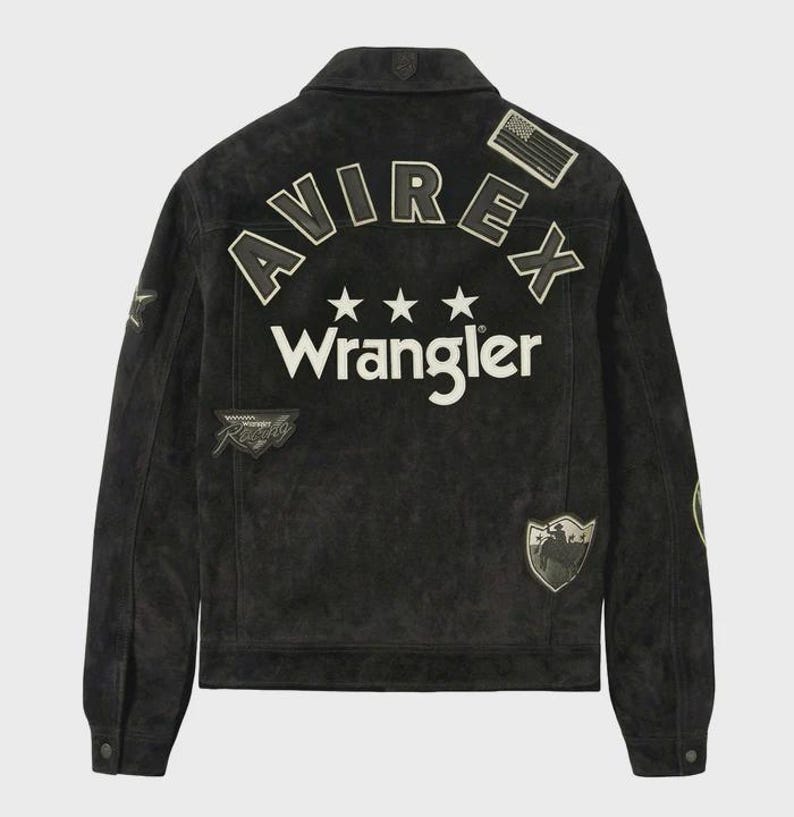 Puede incluir: Una chaqueta de ante negro con el texto AVIREX y Wrangler en letras blancas en la espalda. El dise&ntilde;o incluye tres estrellas blancas, un peque&ntilde;o parche de la bandera estadounidense, un parche de Wrangler Racing y un parche en forma de escudo con un vaquero.