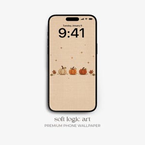 Può includere: Uno smartphone che mostra uno sfondo digitale con un motivo a punto croce di tre zucche e foglie autunnali su sfondo beige. Lo schermo mostra l'ora 9:41 e martedì 9 gennaio. Sotto il telefono è presente il testo soft logic art.