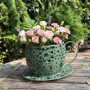 Dekorativ metallblomkruka i form av en kopp med fat