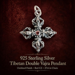 May include: A 925 sterling silver Tibetan double vajra pendant with an oxidised finish and a central red cubic zirconia stone. The pendant features intricate metalwork and includes a 70.1 cm chain. Text reads: 925 Sterling Silver Tibetan Double Vajra Pendant, Oxidised Finish, Red CZ, 27.6 in Chain.