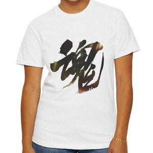 以下が含まれることがあります： 黒と茶色の書道デザインが特徴の白いTシャツ。 デザインは芸術的なレタリングの一種です。 シャツは柔らかく快適な素材で作られています。