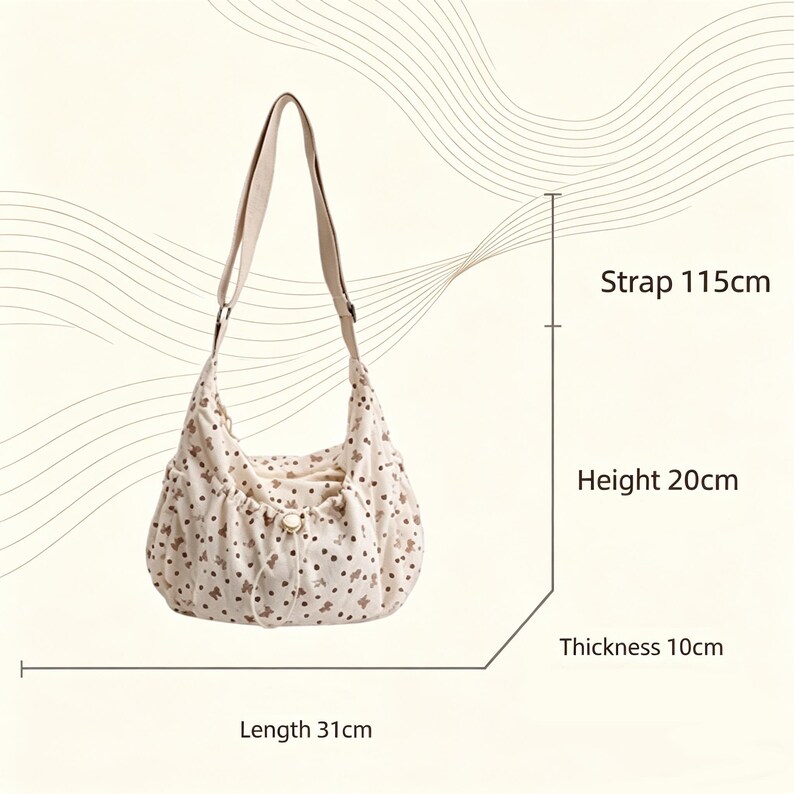 May include: Cream-colored shoulder bag with a floral pattern. The bag has a strap that is 45 inches long, a height of 8 inches, a length of 12 inches, and a thickness of 4 inches. The bag has a drawstring closure and a button.