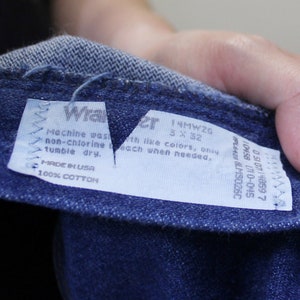 May include: A blue denim label with white text that reads "Machine wash with like colors, only bleach when needed. Made in USA 100% Cotton" and "14MWZG 3X32".