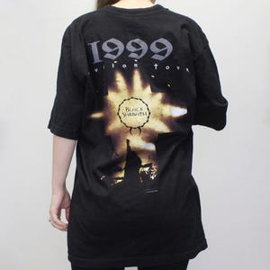 May include: Black t-shirt with a graphic print of a cross with the text "1999 Reunion Tour" and "Black Sabbath" in a circle.