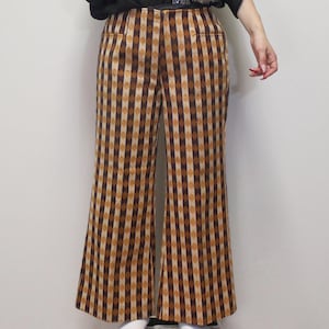 以下が含まれることがあります： 茶色、タン、クリーム色の幾何学模様のワイドパンツ。ハイウエストでフレアの脚。生地は織り込まれているようです。ヴィンテージスタイルです。