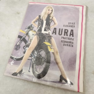May include: A vintage advertisement poster featuring a person with blonde hair wearing a dark sleeveless top and skirt, standing over a motorcycle. The text reads LAURA, STILE, ELEGANZA, PRATICITA, ECONOMIA, DURATA. The poster has a light purple background.