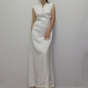Puede incluir: Un vestido maxi blanco con un corpiño de encaje y un escote alto. El vestido tiene un diseño simple y elegante y es perfecto para una ocasión especial.