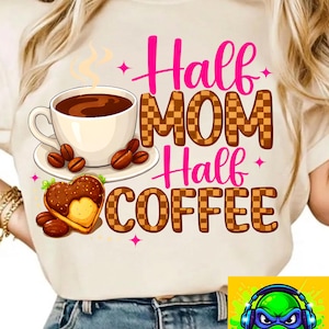 May include: A cream-colored t-shirt features the text "Half Mom Half Coffee" in pink and brown checkered letters. A coffee cup, coffee beans, and a heart-shaped cookie are also displayed on the shirt. The shirt is a casual wear item.