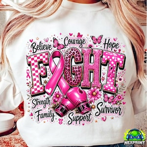 May include: A white sweatshirt featuring a graphic with the word FIGHT in pink patterns, a pink awareness ribbon, and two pink boxing gloves. The design includes butterflies, flowers, hearts, and the words Believe, Courage, Hope, Strength, Family, Support, Survivor.
