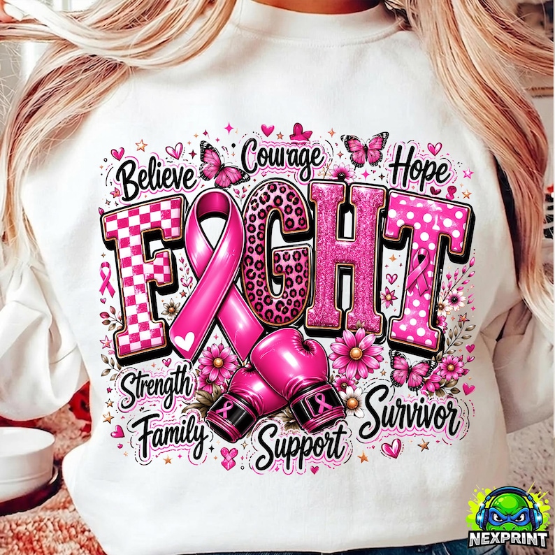 May include: A white sweatshirt featuring a graphic with the word FIGHT in pink patterns, a pink awareness ribbon, and two pink boxing gloves. The design includes butterflies, flowers, hearts, and the words Believe, Courage, Hope, Strength, Family, Support, Survivor.