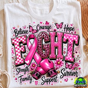 May include: A white t-shirt featuring a graphic design with the word FIGHT in large pink letters, a pink awareness ribbon, and two pink boxing gloves. The design includes butterflies, flowers, and the words Believe, Courage, Hope, Strength, Family, Support, and Survivor.