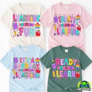 Puede incluir: Cuatro camisetas de manga corta en crema, rosa claro, azul claro y verde oscuro. Cada camiseta presenta texto gráfico colorido e ilustraciones de un cuaderno, lápiz, estrella y manzana con lazos, incluyendo frases como Learning Is Fun.