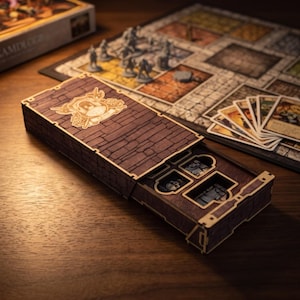 May include: A rectangular wooden storage box with a dark brown brick pattern and a laser-cut emblem on the lid featuring the word QUEST. The box has a sliding tray compartment revealing internal slots for game components, positioned near a board game.