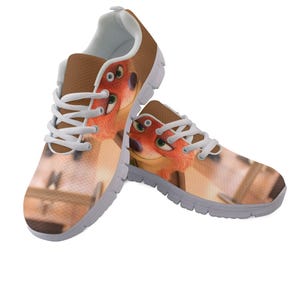 May include: A pair of trainers featuring a cartoon fox design. The shoes have a brown upper with white laces and a white interior. The fox graphic is orange and brown with green eyes. The soles are grey.