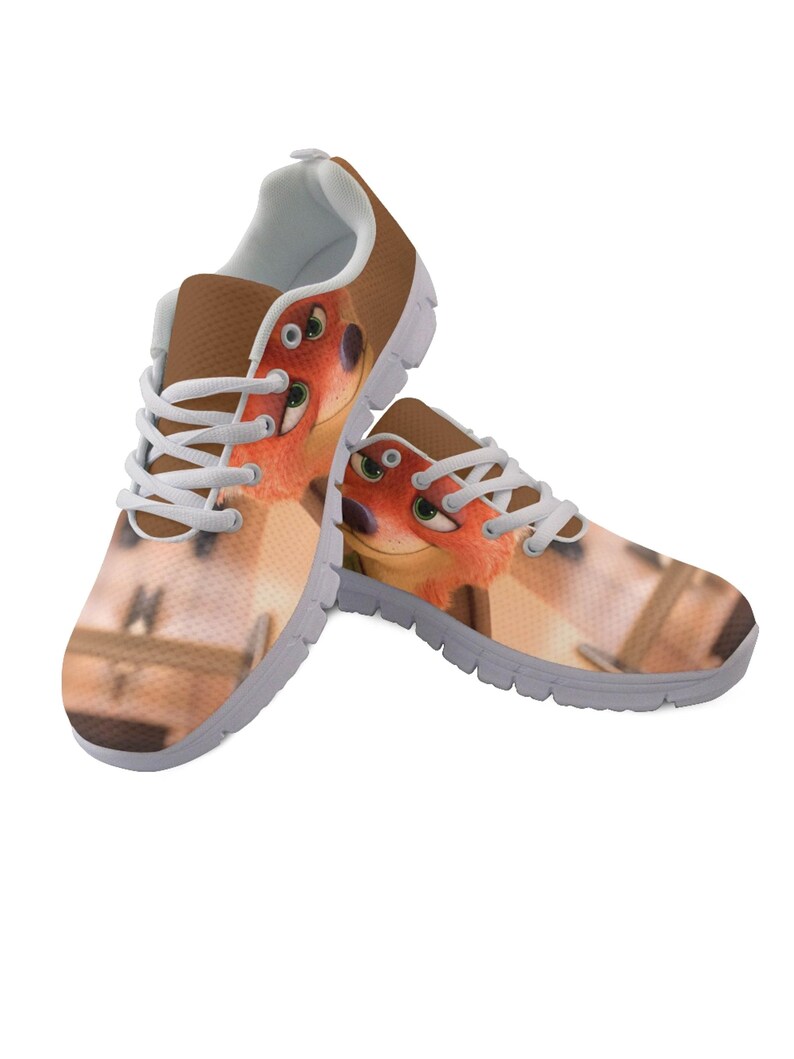 May include: A pair of trainers featuring a cartoon fox design. The shoes have a brown upper with white laces and a white interior. The fox graphic is orange and brown with green eyes. The soles are grey.