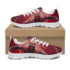 K&ouml;nnte beinhalten: Rote und wei&szlig;e Sportschuhe mit einem Spider-Man-Motiv. Die Schuhe haben ein rotes Mesh-Obermaterial mit einem Spider-Man-Bild sowie wei&szlig;e Schn&uuml;rsenkel und Sohlen. Die Schuhe werden auf einem braunen Karton pr&auml;sentiert.