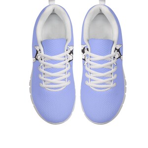 May include: Light blue trainers with white laces and soles. The shoes have a black and white cartoon cow design on the sides. These trainers are designed for comfort and style, suitable for everyday wear.