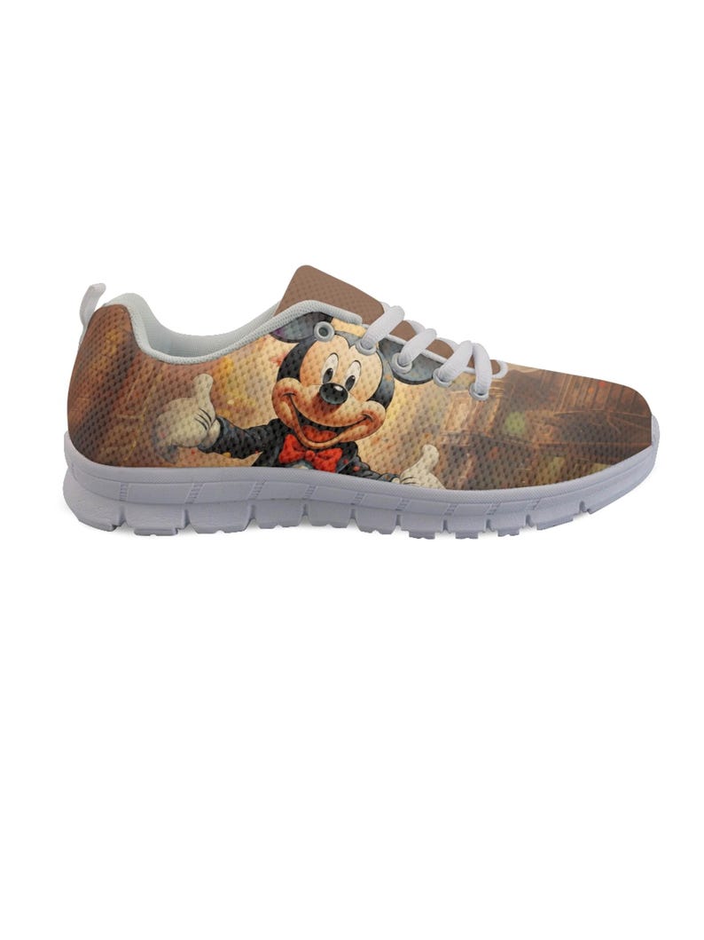 Pu&ograve; includere: Un paio di scarpe sportive con un'immagine a cartoni animati di Topolino. Le scarpe hanno uno sfondo marrone e beige con una suola bianca e lacci bianchi. Topolino indossa un abito nero e un papillon rosso.