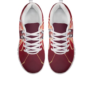K&ouml;nnte beinhalten: Paar rote Sportschuhe mit wei&szlig;en Schn&uuml;rsenkeln und Sohlen. Die Schuhe haben ein grafisches Design mit goldenen Akzenten und einem Superhelden-Thema. Die Schuhe sind auf Komfort und Stil ausgelegt.