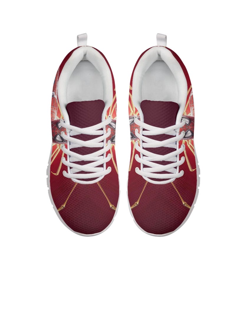 K&ouml;nnte beinhalten: Paar rote Sportschuhe mit wei&szlig;en Schn&uuml;rsenkeln und Sohlen. Die Schuhe haben ein grafisches Design mit goldenen Akzenten und einem Superhelden-Thema. Die Schuhe sind auf Komfort und Stil ausgelegt.