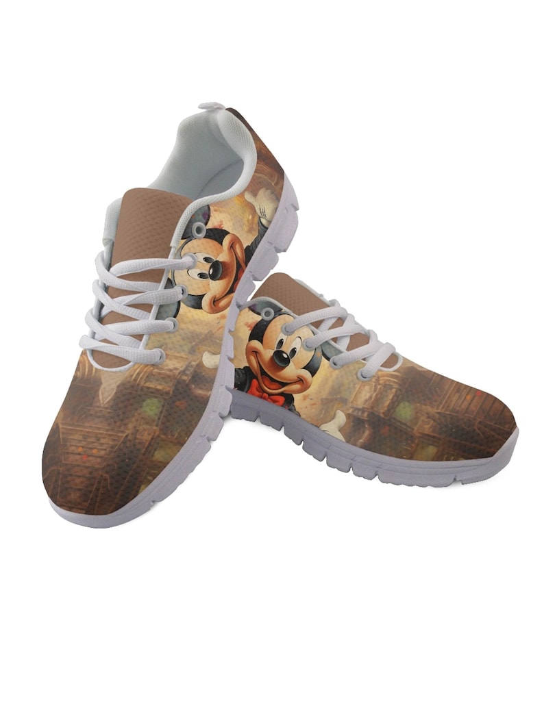 Pu&ograve; includere: Un paio di scarpe sportive con un'immagine a cartoni animati di Topolino. Le scarpe hanno una combinazione di colori marrone e bianco, con lacci e suole bianche. Il design include un'illustrazione dettagliata di Topolino sui lati.