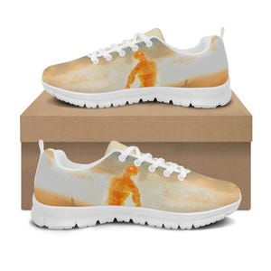 May include: Pair of athletic shoes with a white sole and laces. The uppers feature a light orange and white design with an orange figure. The shoes are displayed on a brown cardboard box.