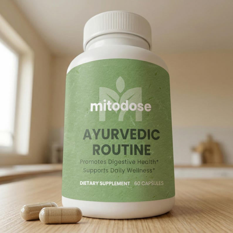 Puede incluir: Una botella blanca de suplemento diet&eacute;tico "mitodose" Ayurvedic Routine con una etiqueta verde. La etiqueta incluye texto que promueve la salud digestiva y el bienestar diario. Dos c&aacute;psulas est&aacute;n frente a la botella.