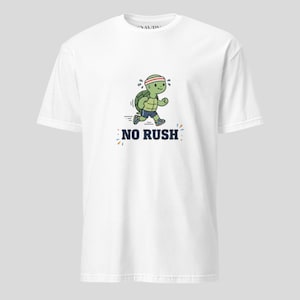 May include: White t-shirt featuring a cartoon turtle running with a red headband and blue shorts. The text "NO RUSH" is printed below the turtle in navy blue. The design includes small blue and orange accents.