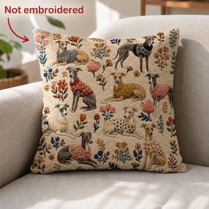 Könnte beinhalten: Ein quadratisches Dekokissen mit cremefarbenem Hintergrund und einem wiederkehrenden Muster aus Windhunden in verschiedenen bunten Strickpullovern, durchsetzt mit kleinen Blumenmotiven. Der Text "Not embroidered" ist oben links sichtbar.