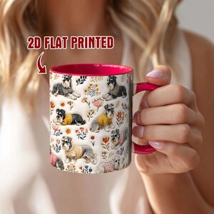 Puede incluir: Una taza de cerámica con interior y asa de color rosa brillante, con un patrón repetitivo de perros Schnauzer con suéteres intercalados con coloridas ilustraciones florales. El texto 2D FLAT PRINTED es visible sobre la taza.