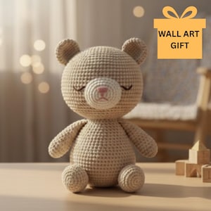 Op de afbeelding: Een beige gehaakte teddybeer met gesloten ogen en een roze neus. De beer heeft een getextureerd oppervlak en zit rechtop. De afbeelding bevat een cadeau-doosafbeelding met de tekst "WALL ART GIFT".